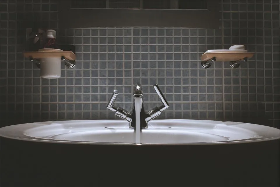 Badkamer met vrijstaande wastafel en donkere wandtegels