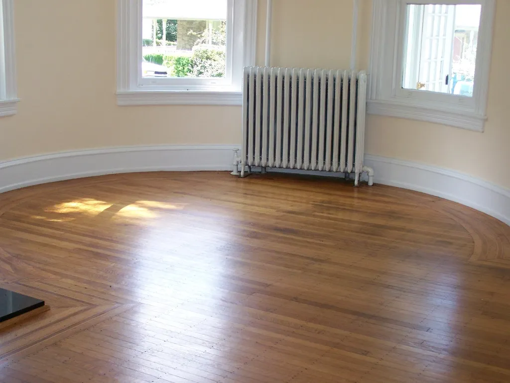 Lege kamer met houten vloer en radiator onder het raam