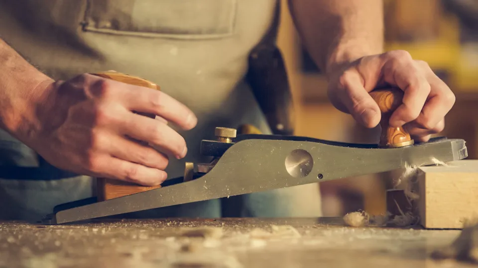 Vakman schaaft een houten plank met een handschaaf