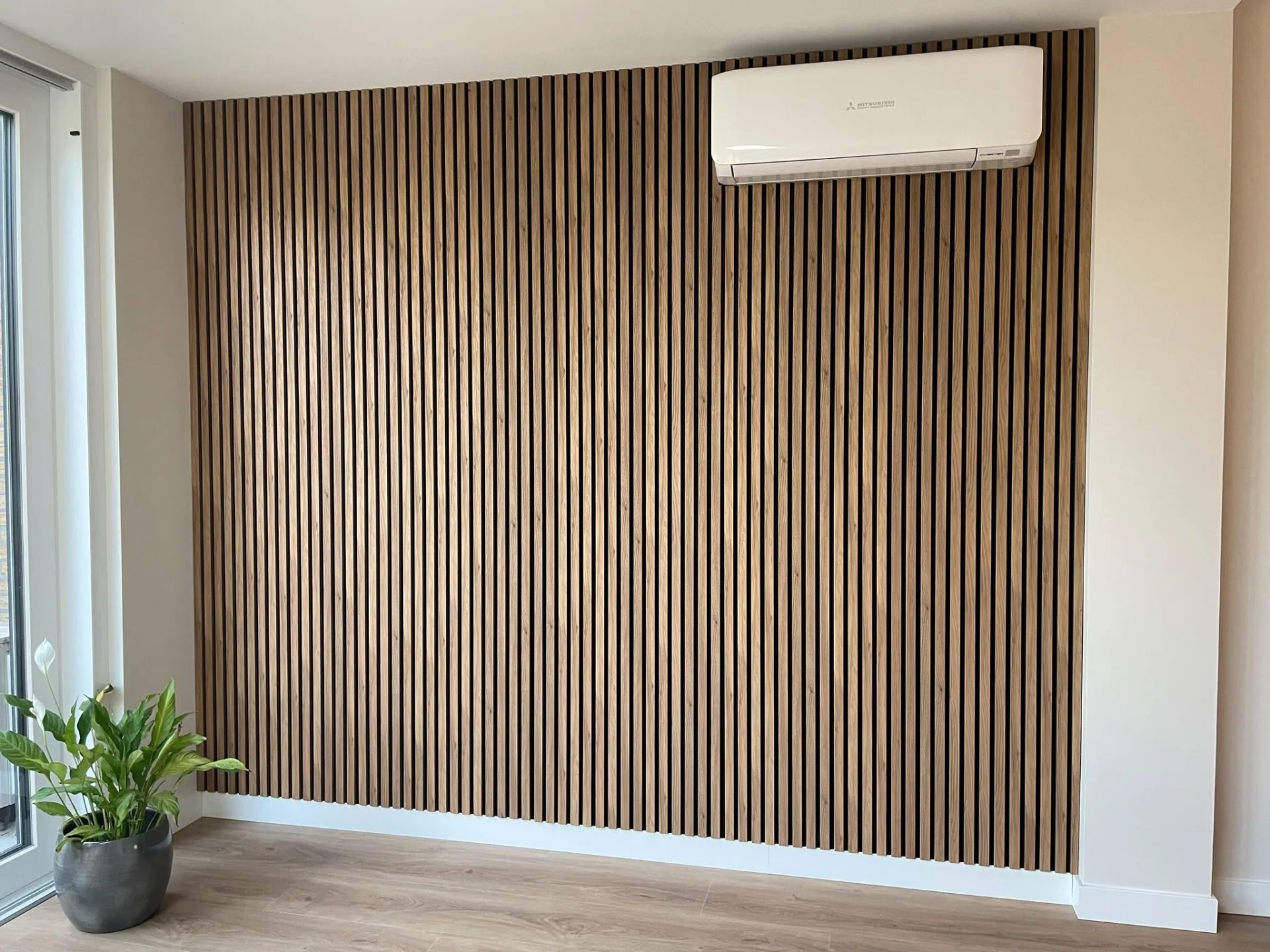 Houten lamellenwand over de volle breedte van een woonkamer met airco-unit